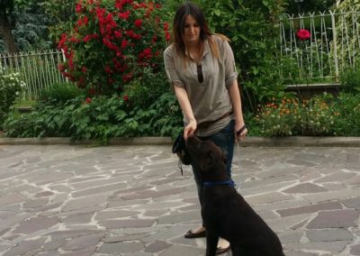 Proprietaria gioca in giardino con il suo labrador nero attento davanti a lei