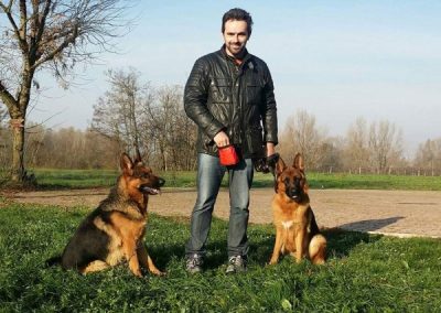 Conduttore con due Pastori Tedeschi seduti ai lati durante l'addestramento